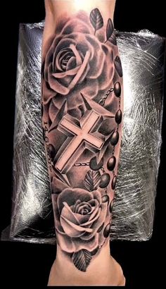 a cross and roses tattoo on the leg is shown in black and grey colors,