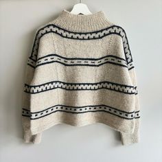 a sweater hanging on a wall with a hanger in front of it that has a white and black striped pattern