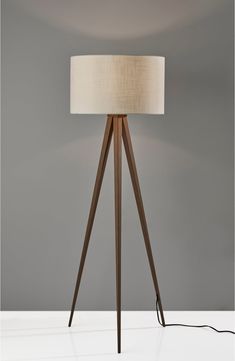 a lamp that is sitting on top of a white tablecloth with a beige shade over it