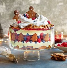 a cake decorated with gingerbreads, raspberries and other holiday treats sits on a table