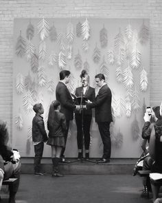 black and white photograph of two men shaking hands in front of a group of people