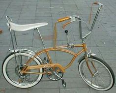 an orange and white bicycle is parked on the sidewalk