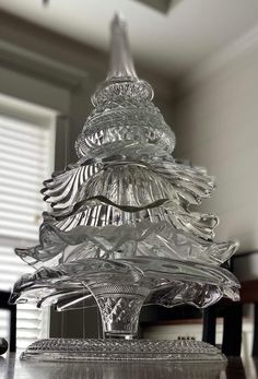 a glass christmas tree sitting on top of a wooden table