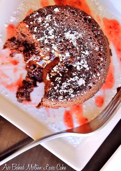 a piece of chocolate cake with powdered sugar on top and a fork in the foreground