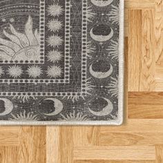 an area rug with sun and moon designs on the floor next to a wood floor