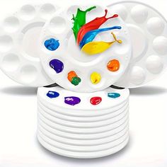 a stack of white plates with different colored paints on them