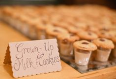 small cookies are on display in front of a sign that says, grown up milk and cookies