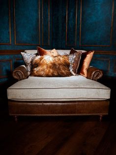 a couch with two pillows on top of it in front of a blue wall and wooden floor