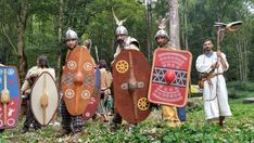 several men dressed in medieval costumes standing next to each other with shields and spears on their heads