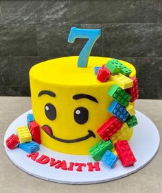 a birthday cake made to look like a smiley face with legos around it and the number seven on top