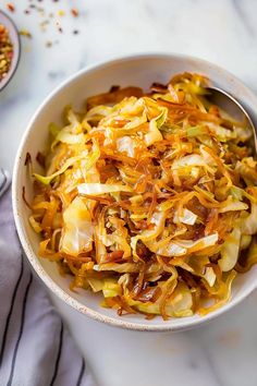 a white bowl filled with coleslaw next to a spoon