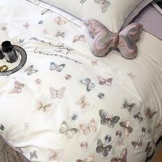 a white bed with butterflies on it and a pair of shoes sitting on the pillow