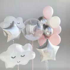 some balloons are in the shape of stars and clouds with eyes on them, one is silver and the other is pink