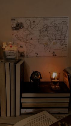 an open book on a table with a lit candle in front of it next to two books