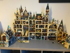 a table topped with lots of legos on top of it's shelf next to a wall