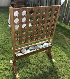 a wooden board game sitting on top of green grass in front of a fenced yard