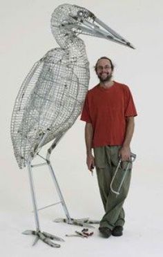 a man standing next to a large metal bird