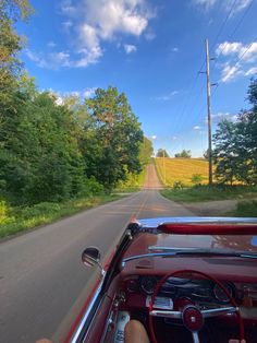 a car driving down a road next to a lush green forest