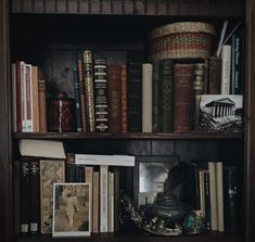 a book shelf filled with lots of books next to a wicker basket and other items