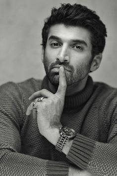 a black and white photo of a man holding his finger to his mouth while looking at the camera