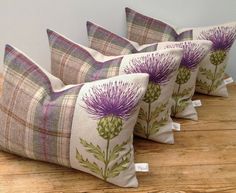 four pillows with thistle designs on them sitting on a wooden floor