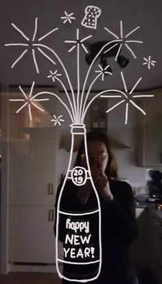 a woman taking a selfie in front of a bottle with fireworks coming out of it