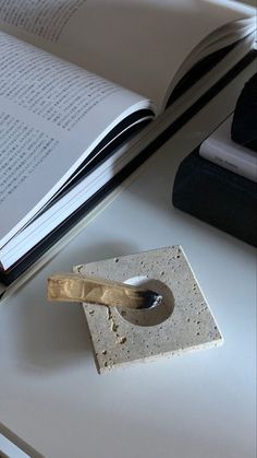 an open book sitting on top of a white table next to a knife and some books