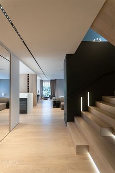 the interior of a modern house with wood flooring and white walls, along with stairs leading up to an open living area