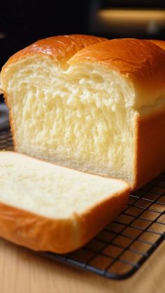 a loaf of bread sitting on top of a cooling rack next to a slice of bread