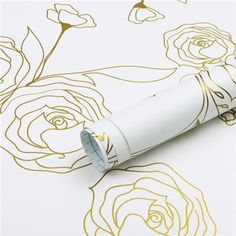 a close up of a pen on a paper with gold foil flowers in the background