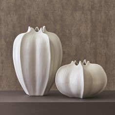 two white vases sitting next to each other on a table