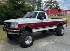 a red and white pickup truck parked in a parking lot