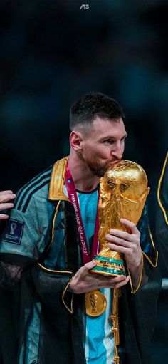 a man holding a soccer ball in his hand and wearing a jacket with the world cup on it