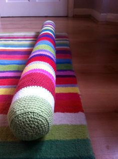 a multicolored rug on the floor with a rolled up object in front of it