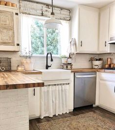 a kitchen with white cabinets and wooden counter tops, an area rug in front of the sink