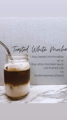 a glass jar filled with liquid sitting on top of a table next to a sign that says toasted white chocolate