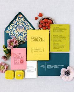 the wedding stationery is laid out on top of each other, with flowers and candy