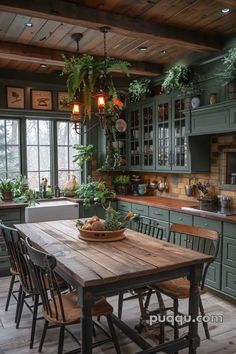 a kitchen with green cabinets and wooden table surrounded by chairs, potted plants on the windowsill