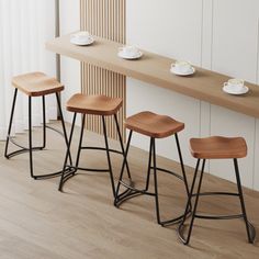 three wooden stools in front of a counter with cups and saucers on it