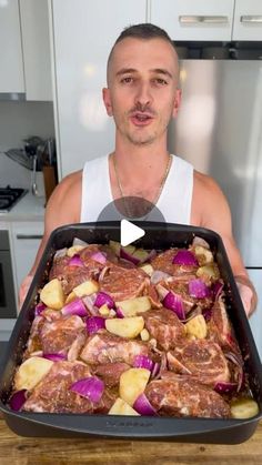 a man holding a pan full of meat and potatoes