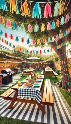 an outdoor dining area with picnic tables and colorful tassels hanging from the trees