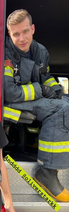 a woman sitting in the back of a fire truck next to a man wearing safety gear