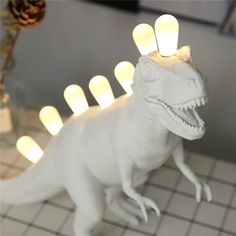 a white toy dinosaur with lights on its head and teeth in it's mouth