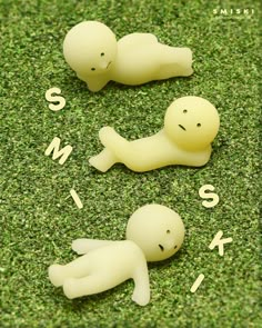 three small plastic figures laying on top of green grass