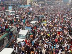 a large group of people standing in the middle of a street with buses and cars