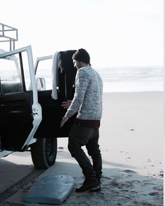 a man standing next to a truck on the beach