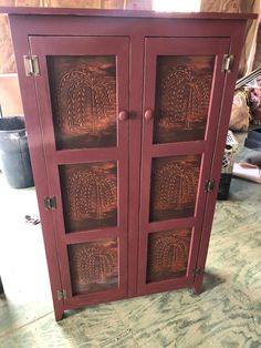 a wooden cabinet with carved designs on the front and side doors, sitting in a room