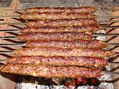 several skewers of meat cooking on an open grill