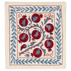 an embroidered square with red and blue flowers on it, in the center is a leafy border