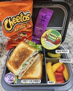 a lunch box with sandwiches, fruit and chips